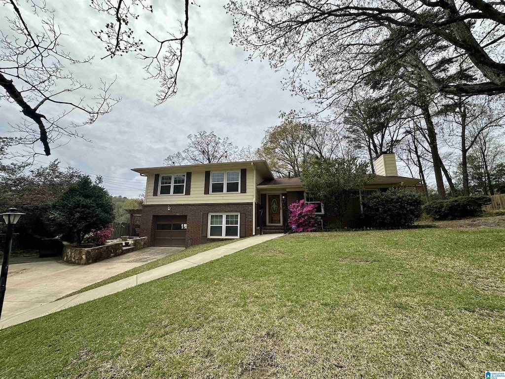 split level home featuring brick siding, driveway, a front lawn, and an attached garage
