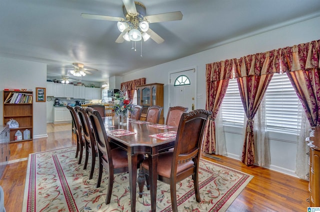 dining room featuring baseboards, ceiling fan, and light wood-style flooring