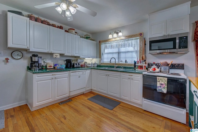 kitchen featuring stainless steel microwave, a sink, visible vents, white dishwasher, and electric stove