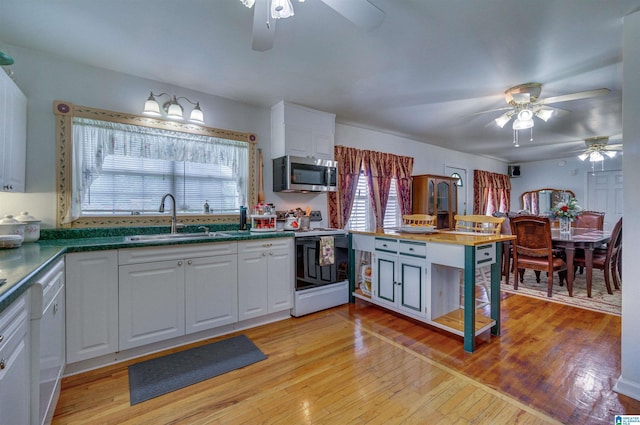 kitchen featuring stainless steel microwave, electric range, a sink, white cabinetry, and a ceiling fan