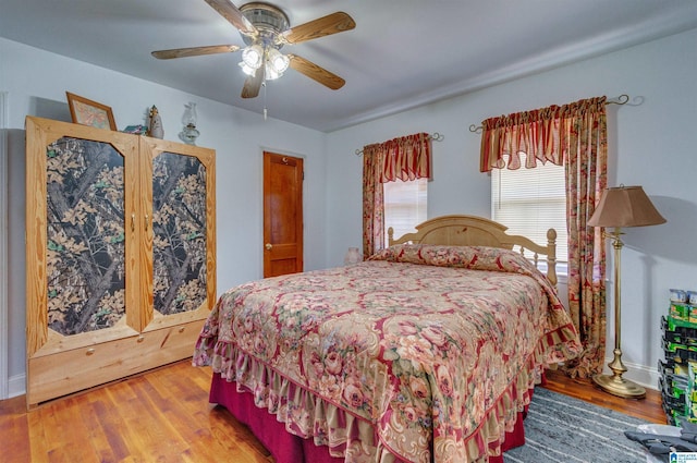 bedroom featuring wood finished floors, a ceiling fan, and baseboards