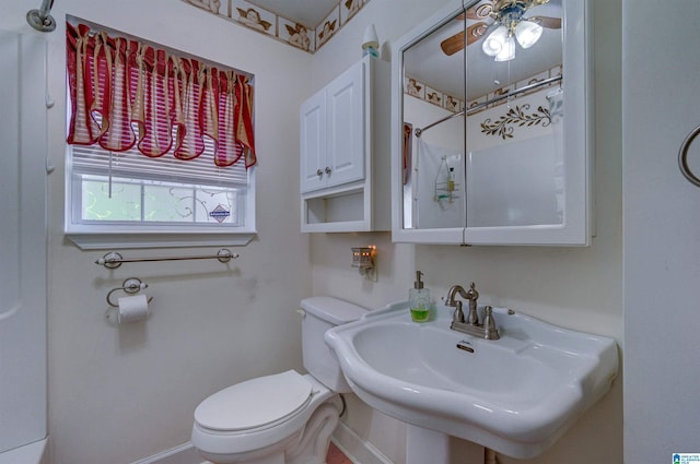 bathroom with curtained shower, a sink, ceiling fan, baseboards, and toilet