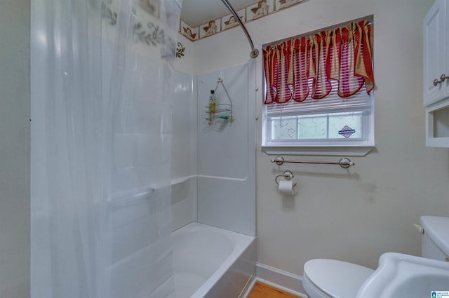 bathroom featuring toilet, shower / bath combo, and baseboards