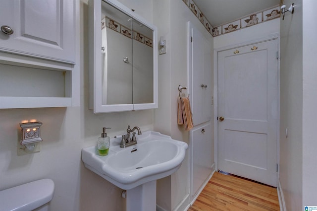 half bath featuring wood finished floors, toilet, and a sink