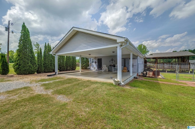 exterior space with fence, a carport, a patio area, and a lawn