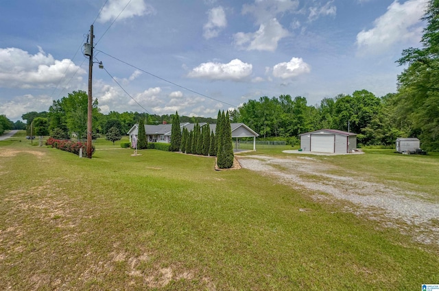 view of yard featuring an outdoor structure, a detached garage, and driveway