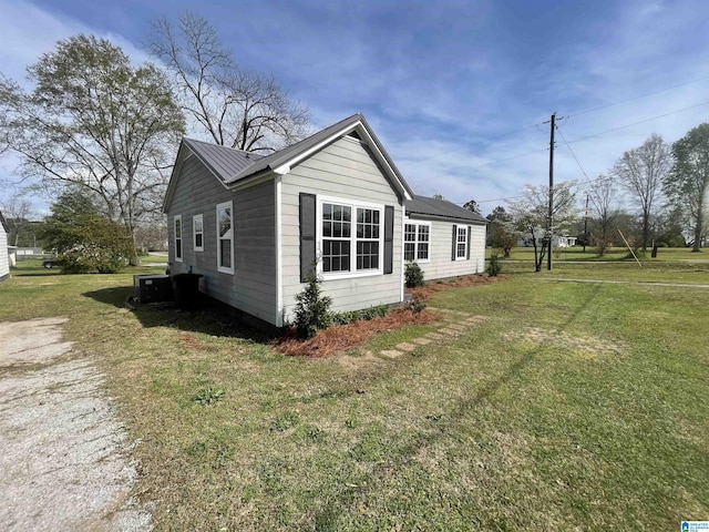 view of home's exterior featuring metal roof, central AC, and a yard