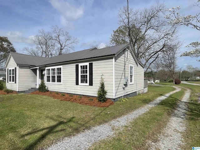 view of property exterior with driveway, a yard, and metal roof
