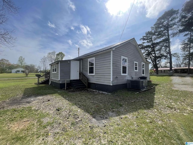 view of front of home with a front lawn, central AC unit, and entry steps