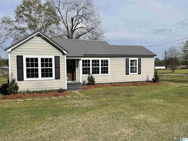view of front of house with metal roof and a front lawn