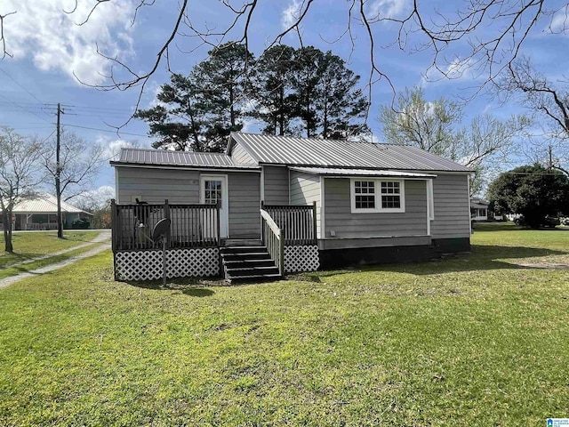 rear view of property featuring a yard, a deck, and metal roof