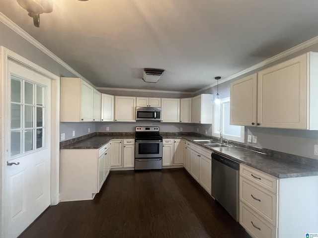 kitchen featuring dark wood-style flooring, ornamental molding, stainless steel appliances, dark countertops, and a sink
