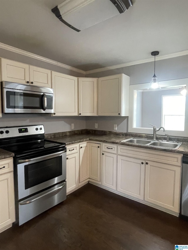 kitchen featuring crown molding, a sink, dark wood-style floors, stainless steel appliances, and dark countertops