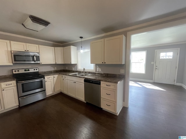 kitchen with ornamental molding, a sink, dark countertops, and appliances with stainless steel finishes