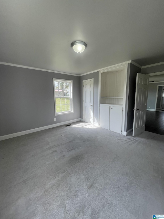 unfurnished bedroom with carpet flooring, crown molding, baseboards, and visible vents