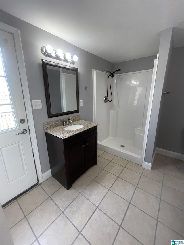 full bath with vanity, baseboards, tile patterned floors, and walk in shower