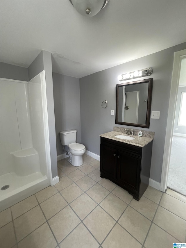 bathroom featuring vanity, toilet, baseboards, tile patterned floors, and walk in shower