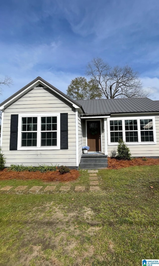 view of front of property featuring metal roof and a front yard