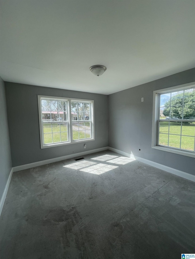 unfurnished room with carpet floors, baseboards, and visible vents