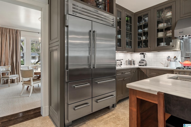 4603 Clairmont Ave, Birmingham, AL 35222 - kitchen featuring stainless steel built in fridge, light countertops, under cabinet range hood, decorative backsplash, and glass insert cabinets