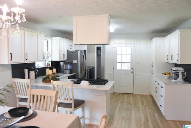 kitchen featuring a peninsula, stainless steel fridge with ice dispenser, light wood-style floors, and a wealth of natural light
