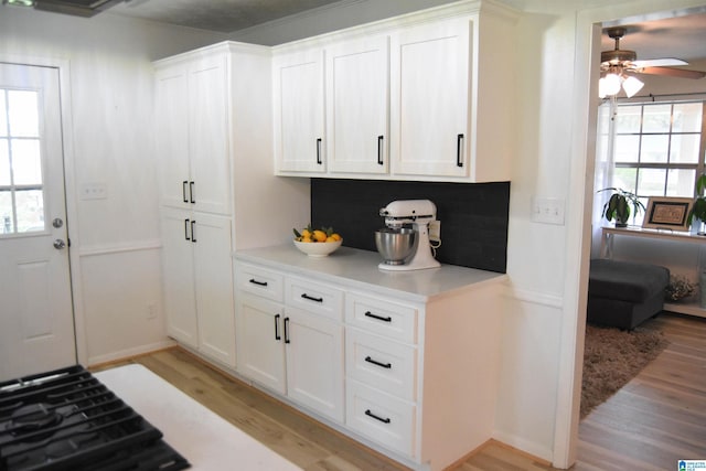 kitchen featuring light countertops, white cabinets, a ceiling fan, and light wood finished floors