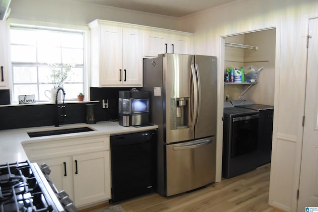 kitchen featuring white cabinets, dishwasher, a sink, stainless steel fridge with ice dispenser, and washer and clothes dryer