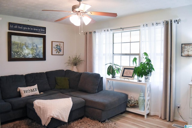 living room featuring visible vents, wood finished floors, and ceiling fan