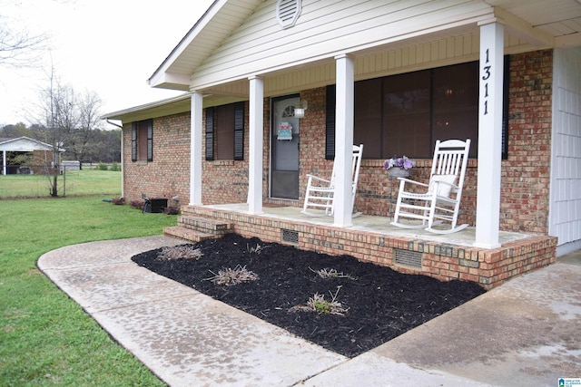 entrance to property featuring brick siding, a porch, and a yard