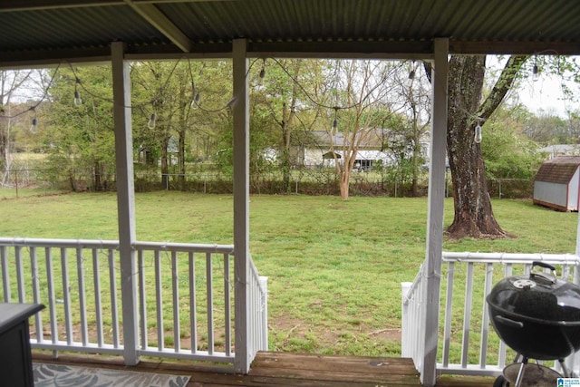 wooden deck featuring a grill, an outbuilding, a fenced backyard, and a yard