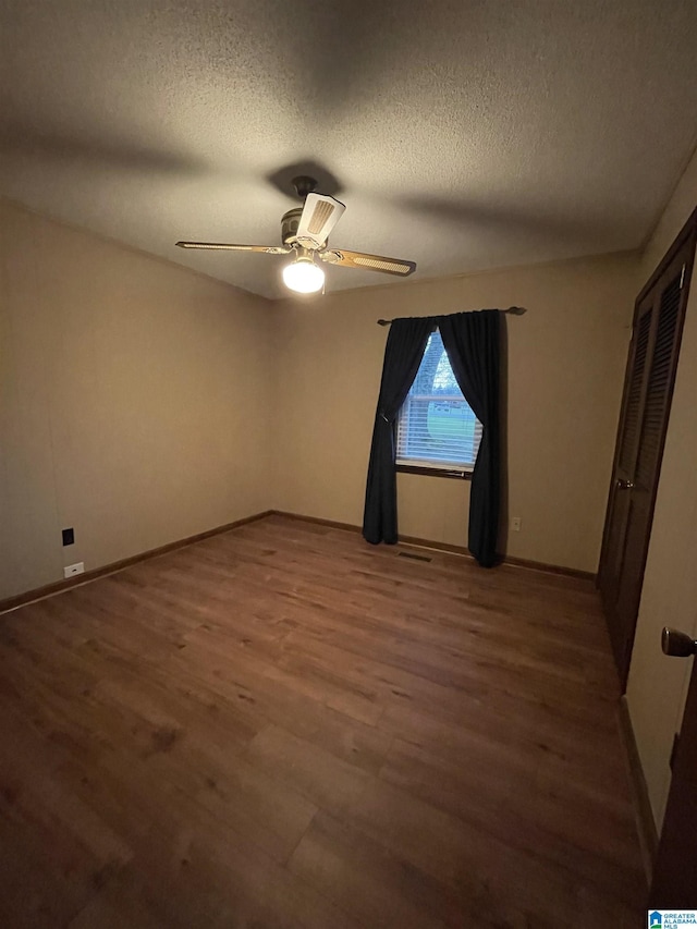 unfurnished bedroom with baseboards, a textured ceiling, a ceiling fan, visible vents, and wood finished floors