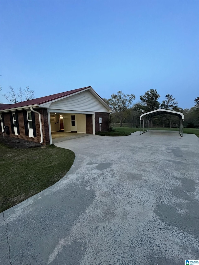 view of property exterior with a detached carport, a lawn, driveway, and brick siding