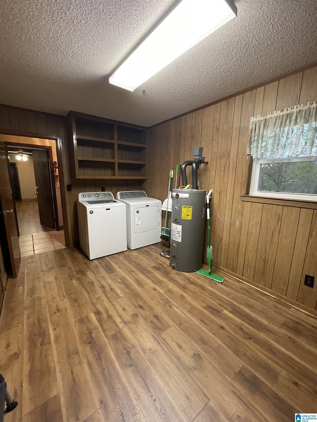 washroom featuring water heater, washer and clothes dryer, laundry area, and wood finished floors