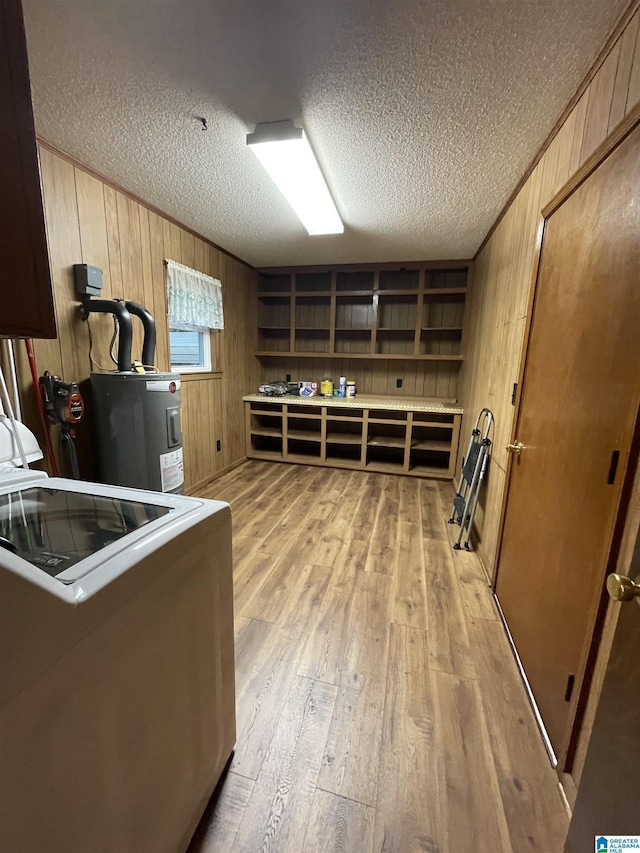 interior space featuring laundry area, light wood-style flooring, a textured ceiling, wood walls, and washer / dryer