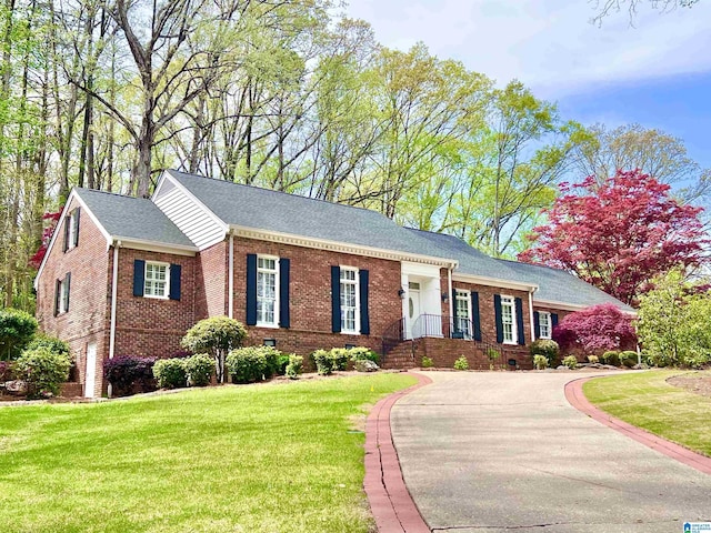 ranch-style home featuring crawl space, brick siding, a front lawn, driveway, and a shingled roof