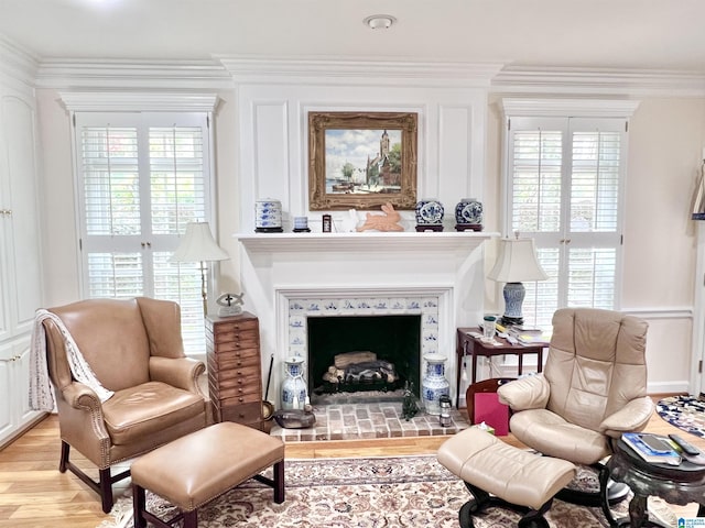 sitting room with a fireplace, light wood-type flooring, and ornamental molding