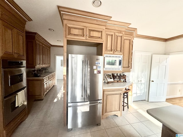 kitchen with light tile patterned flooring, crown molding, light countertops, a sink, and appliances with stainless steel finishes