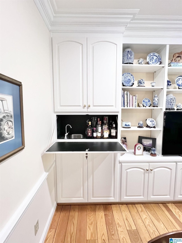 bar with light wood-type flooring and crown molding