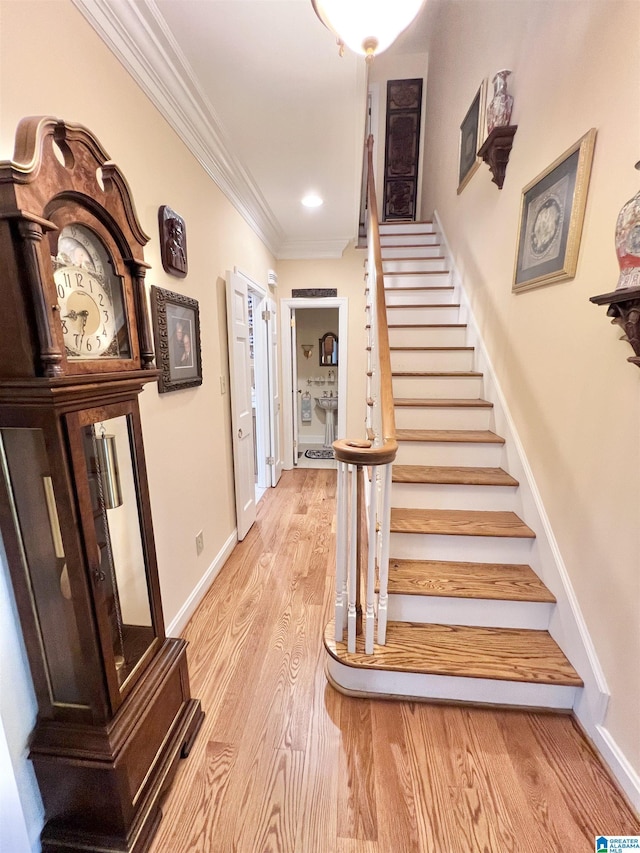stairs with baseboards, wood finished floors, and ornamental molding