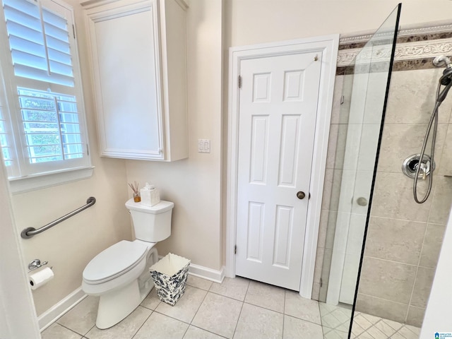 bathroom featuring tile patterned flooring, toilet, baseboards, and a tile shower