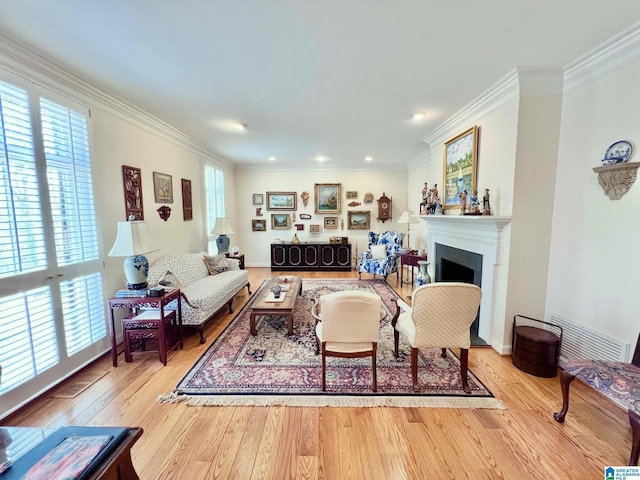 living area with visible vents, a fireplace, crown molding, and wood finished floors