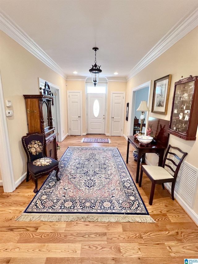 entrance foyer with baseboards, visible vents, crown molding, and light wood-style floors