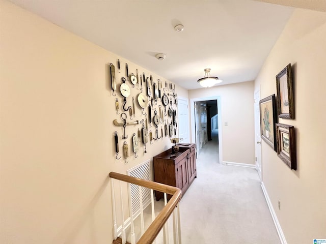 hallway featuring light colored carpet, visible vents, and baseboards