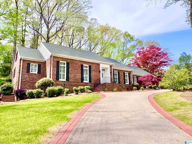 single story home featuring brick siding, a front yard, driveway, and a shingled roof