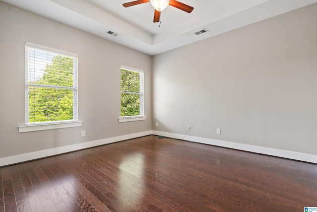 spare room featuring a raised ceiling, plenty of natural light, visible vents, and baseboards