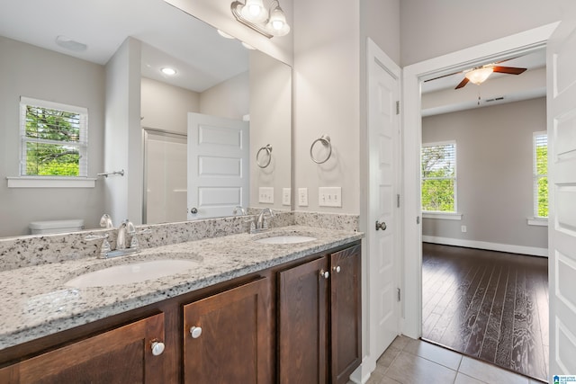 bathroom featuring double vanity, toilet, ceiling fan, and a sink