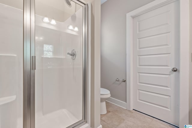 bathroom featuring a shower stall, toilet, tile patterned flooring, and baseboards