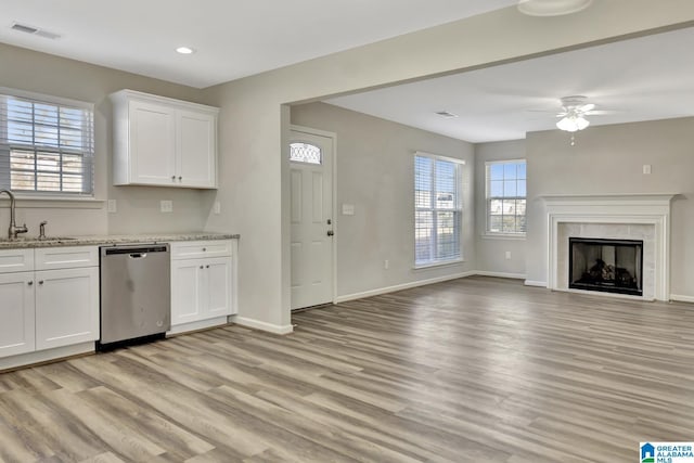kitchen with light wood-type flooring, stainless steel dishwasher, a sink, visible vents, and ceiling fan