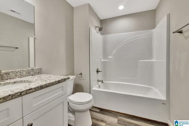 full bath with toilet, vanity, wood finished floors, washtub / shower combination, and visible vents
