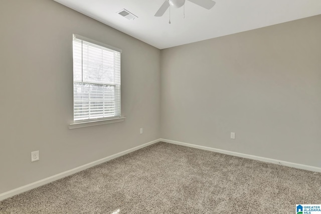 carpeted spare room with visible vents, baseboards, and ceiling fan